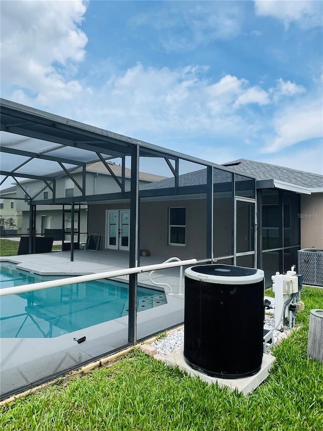 back of house featuring cooling unit, a patio, a lanai, and an outdoor pool
