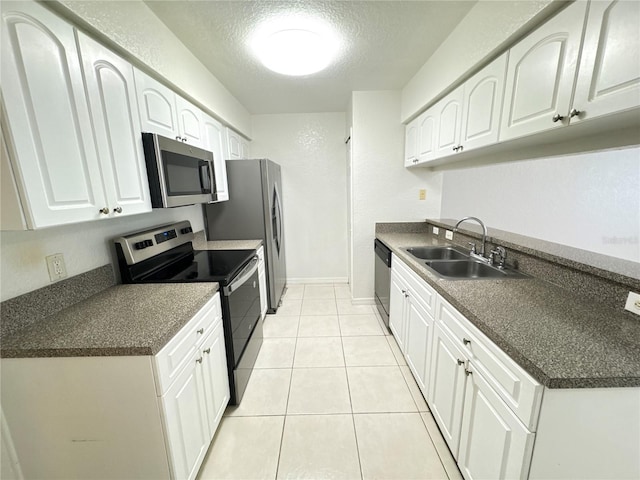 2330 Prime Cir Unit A, Kissimmee, FL 34746 - kitchen with stainless steel appliances, a sink, a textured ceiling, dark countertops, and white cabinetry