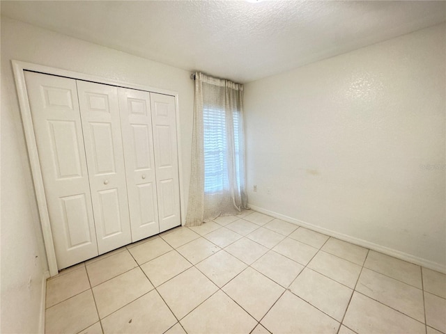 2330 Prime Cir Unit A, Kissimmee, FL 34746 - unfurnished bedroom with light tile patterned floors, a textured ceiling, a closet, and baseboards