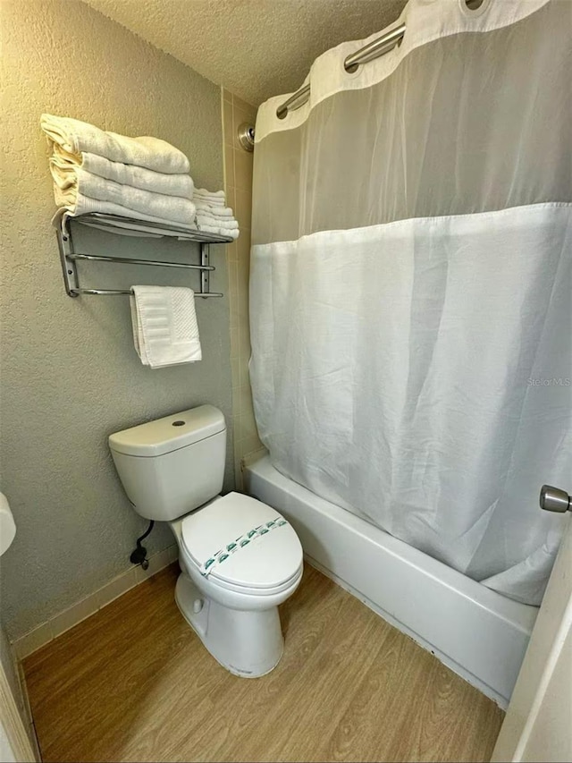 2700 N Atlantic Ave Unit 429, Daytona Beach, FL 32118 - full bathroom with wood finished floors, shower / bathtub combination with curtain, a textured ceiling, a textured wall, and toilet
