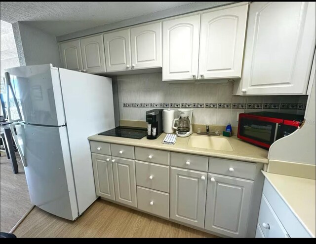 2700 N Atlantic Ave Unit 429, Daytona Beach, FL 32118 - kitchen with freestanding refrigerator, white cabinets, a sink, and light countertops