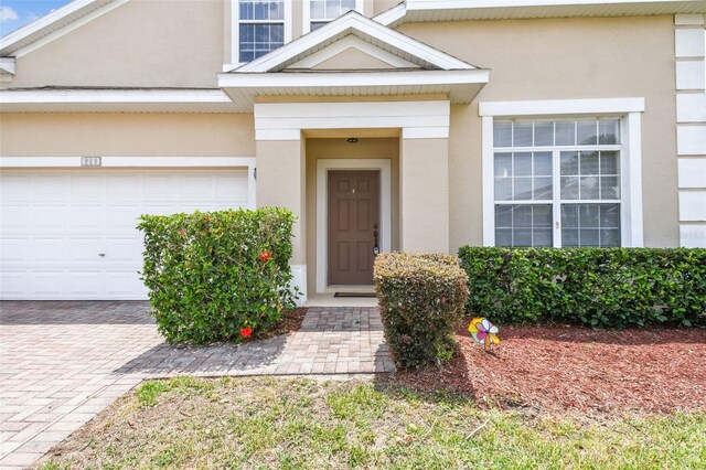 223 Cadiz Loop, Davenport, FL 33837 - view of exterior entry with stucco siding, a garage, and driveway