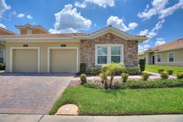 view of front facade with a garage, driveway, a tiled roof, stone siding, and a front yard