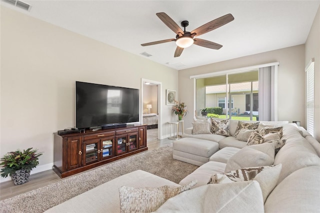 living room featuring a ceiling fan, baseboards, and wood finished floors