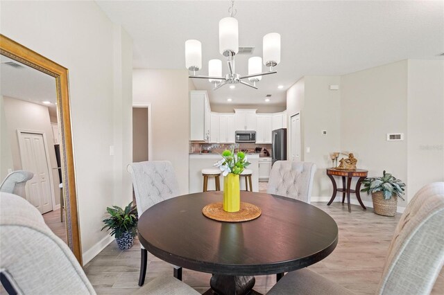dining room with light wood-style flooring, a chandelier, baseboards, and recessed lighting