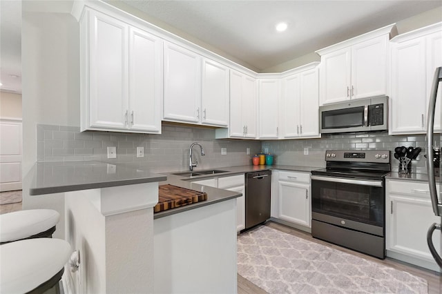 kitchen with appliances with stainless steel finishes, a sink, backsplash, white cabinetry, and recessed lighting