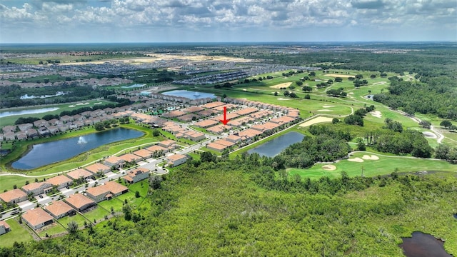 view of property location featuring a golf course, a nearby body of water, and nearby suburban area