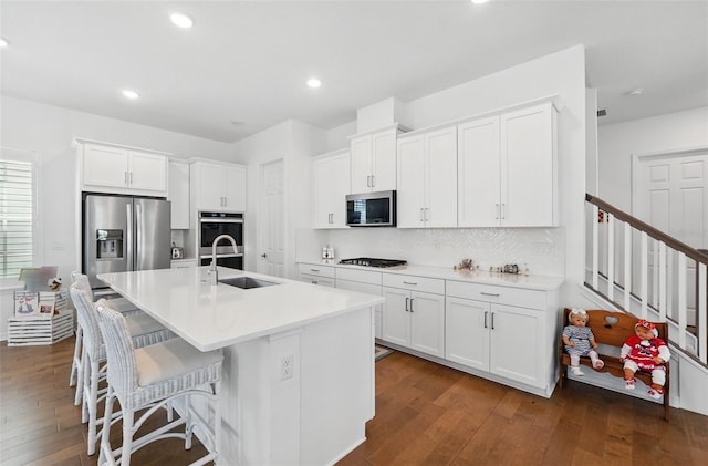 1850 Treasure Cv, Celebration, FL 34747 - kitchen featuring appliances with stainless steel finishes, a sink, dark wood-style floors, white cabinetry, and an island with sink