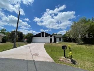 116 Talavera Ln, Kissimmee, FL 34758 - mid-century home with a front lawn, concrete driveway, and a garage