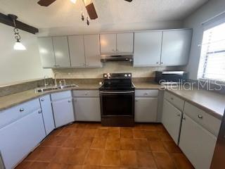 116 Talavera Ln, Kissimmee, FL 34758 - kitchen featuring black range with electric cooktop, under cabinet range hood, ceiling fan, a sink, and dark tile patterned flooring