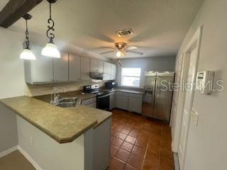 116 Talavera Ln, Kissimmee, FL 34758 - kitchen featuring stainless steel appliances, a sink, a peninsula, a ceiling fan, and hanging light fixtures