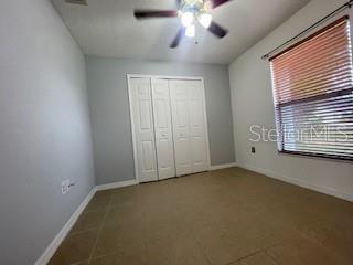 116 Talavera Ln, Kissimmee, FL 34758 - unfurnished bedroom with baseboards, a closet, tile patterned floors, and ceiling fan