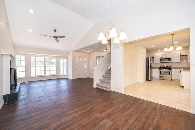 unfurnished living room with a chandelier, light wood-style floors, stairway, a ceiling fan, and baseboards