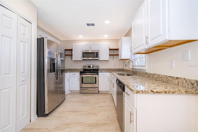 kitchen featuring stainless steel appliances, a sink, white cabinets, light stone counters, and recessed lighting
