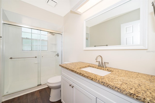 bathroom with a shower stall, toilet, vanity, and wood finished floors