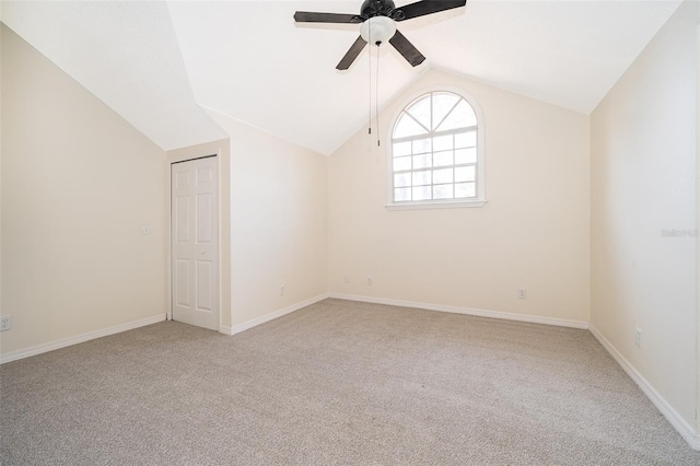 spare room featuring carpet, ceiling fan, lofted ceiling, and baseboards