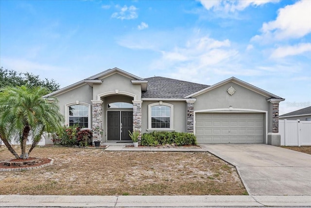 491 Majestic Gardens Blvd, Winter Haven, FL 33880 - view of front of house featuring stucco siding, an attached garage, driveway, fence, and stone siding