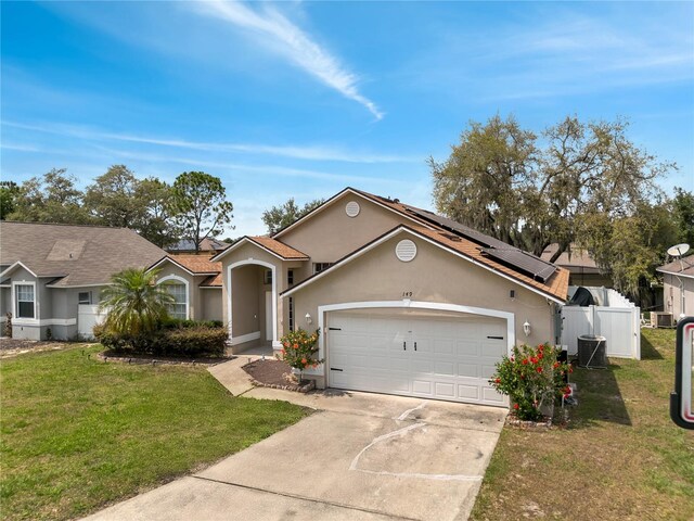 149 Imperial Oak Ct, Davenport, FL 33896 - view of front of house featuring central air condition unit, stucco siding, solar panels, concrete driveway, and a garage