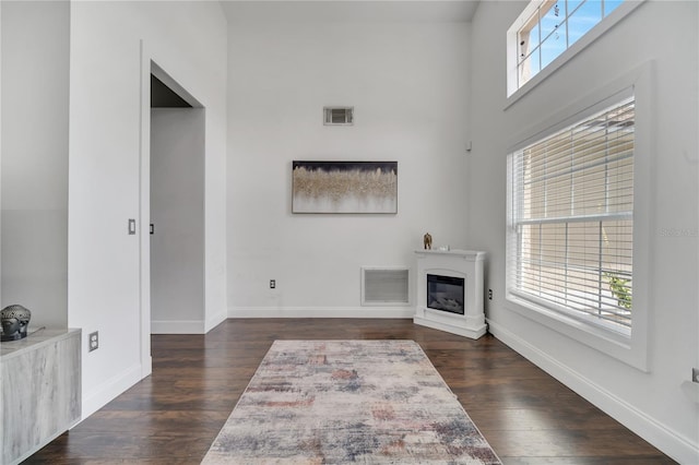 149 Imperial Oak Ct, Davenport, FL 33896 - unfurnished living room featuring dark wood-style flooring, baseboards, a glass covered fireplace, and a high ceiling