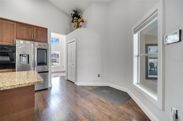 149 Imperial Oak Ct, Davenport, FL 33896 - kitchen featuring stainless steel fridge, black oven, high vaulted ceiling, dark wood finished floors, and baseboards
