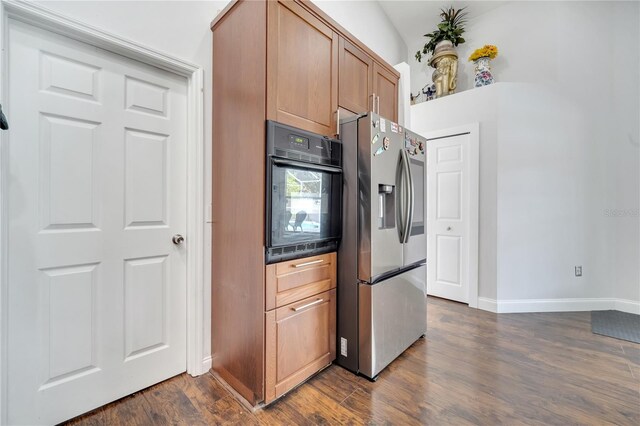 149 Imperial Oak Ct, Davenport, FL 33896 - kitchen with stainless steel fridge with ice dispenser, oven, dark wood-type flooring, baseboards, and brown cabinets