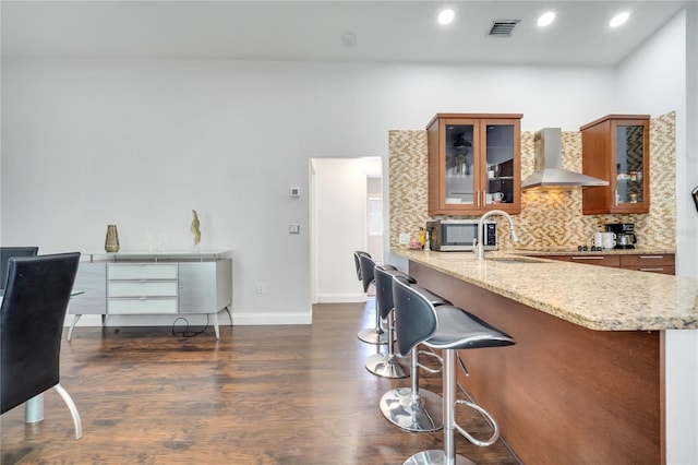 149 Imperial Oak Ct, Davenport, FL 33896 - kitchen with wall chimney exhaust hood, brown cabinetry, dark wood finished floors, a breakfast bar, and recessed lighting