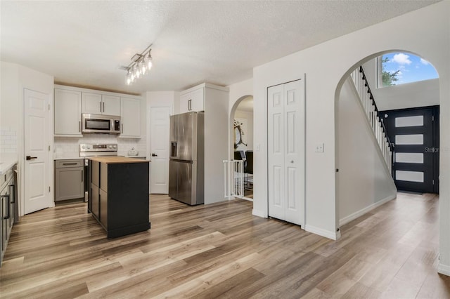 102 Royalty Cir, Sanford, FL 32771 - kitchen with appliances with stainless steel finishes, butcher block countertops, arched walkways, light wood-style floors, and tasteful backsplash