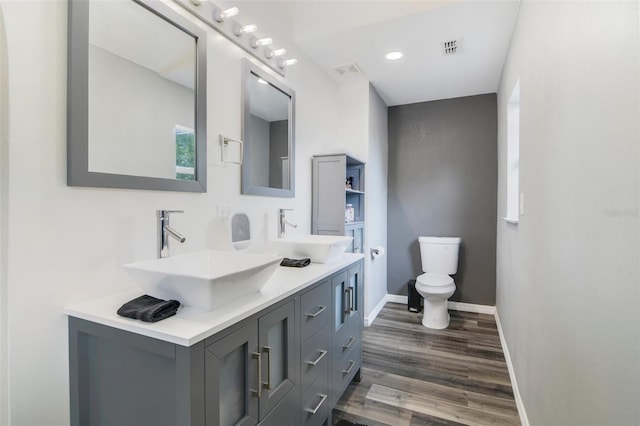 102 Royalty Cir, Sanford, FL 32771 - bathroom with double vanity, wood finished floors, toilet, baseboards, and recessed lighting