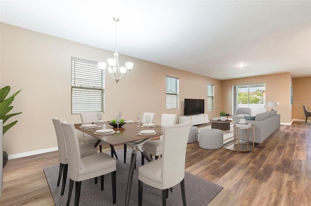 dining area featuring wood finished floors, a chandelier, and baseboards