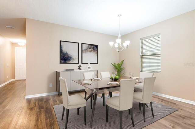dining room with wood finished floors, a chandelier, and baseboards