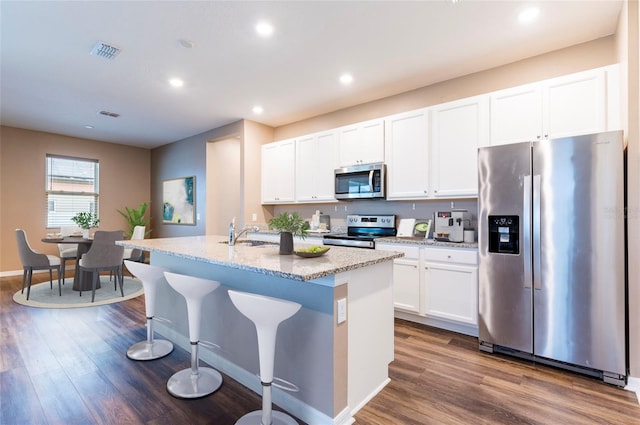 kitchen with stainless steel appliances, dark wood-type flooring, a kitchen island with sink, white cabinets, and recessed lighting
