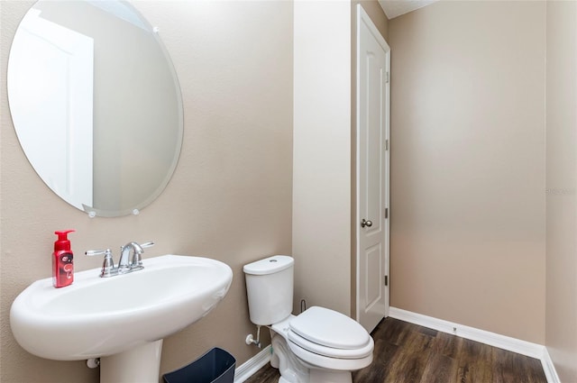 bathroom featuring toilet, wood finished floors, baseboards, and a sink