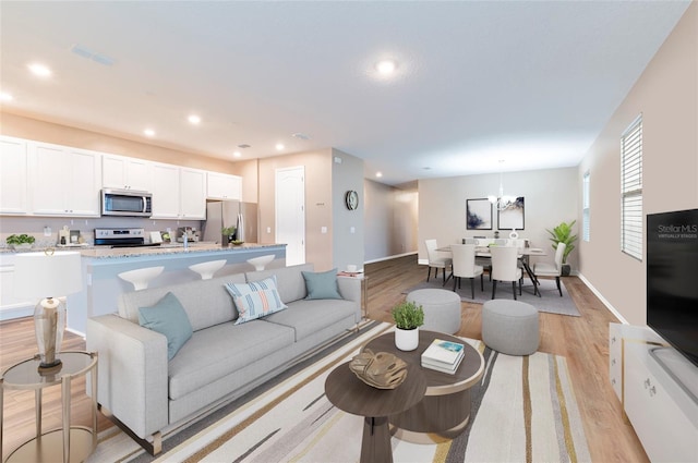 living room with light wood-type flooring, recessed lighting, a chandelier, and baseboards