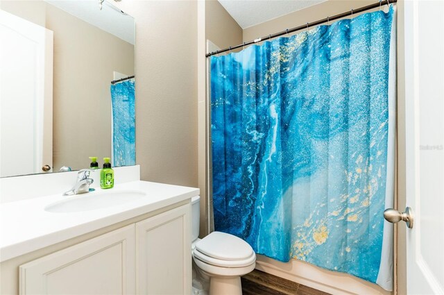 full bath featuring toilet, vanity, wood finished floors, and shower / bath combo with shower curtain
