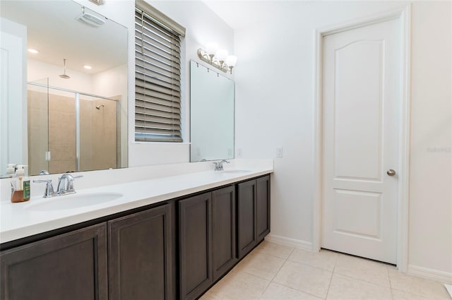 full bath with tile patterned floors, a shower stall, baseboards, and double vanity