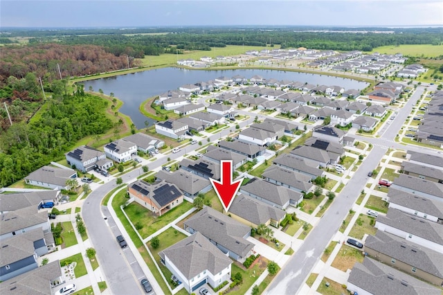 aerial perspective of suburban area featuring a nearby body of water and a forest