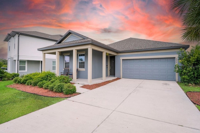 view of front of house featuring covered porch, concrete driveway, a garage, stucco siding, and a front yard