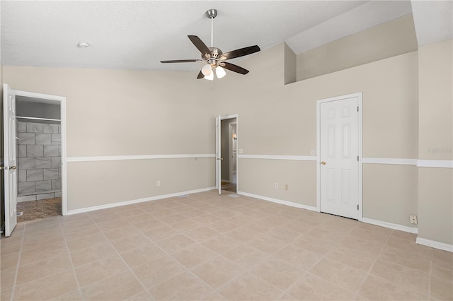 unfurnished bedroom featuring baseboards, light tile patterned flooring, high vaulted ceiling, ensuite bathroom, and ceiling fan