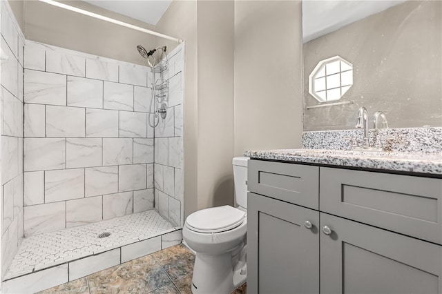 bathroom featuring toilet, a tile shower, and vanity