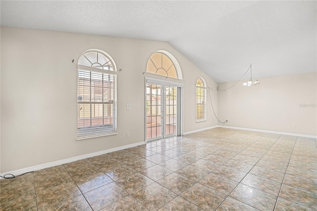spare room featuring a chandelier, lofted ceiling, tile patterned flooring, a textured ceiling, and baseboards