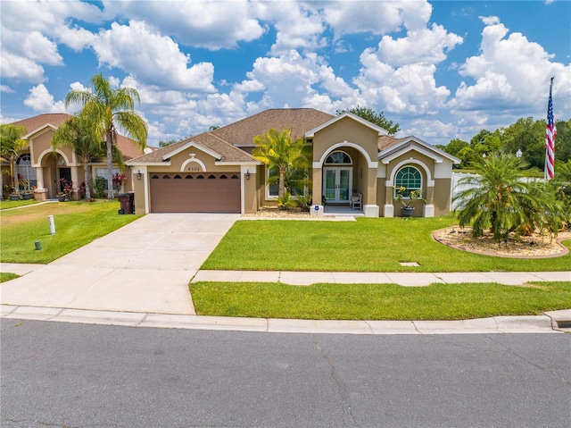 mediterranean / spanish-style house featuring stucco siding, a garage, and a front lawn