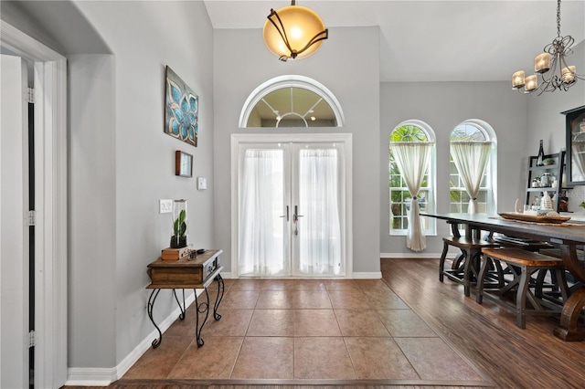 entrance foyer with a chandelier, french doors, tile patterned floors, and baseboards