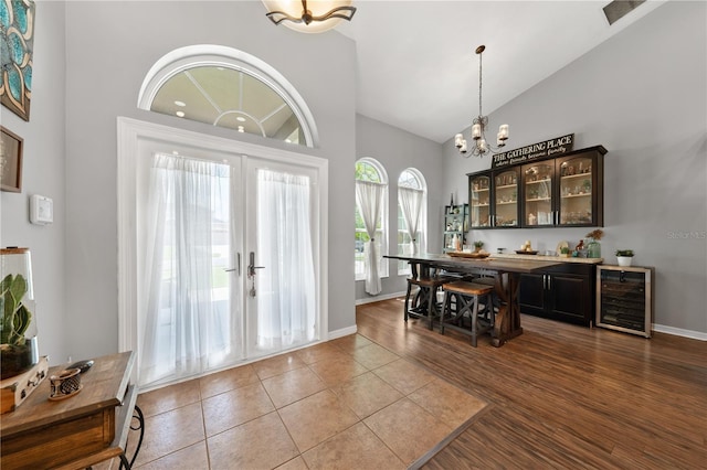 entryway with beverage cooler, a chandelier, high vaulted ceiling, and baseboards