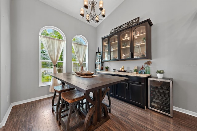 dining room featuring beverage cooler, dark wood-style floors, a chandelier, lofted ceiling, and baseboards