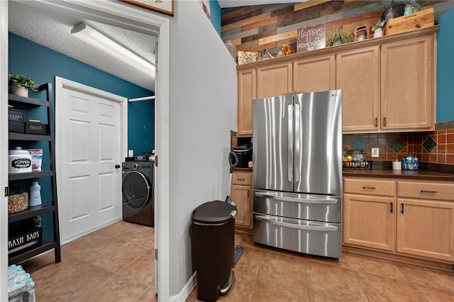kitchen with freestanding refrigerator, washer / dryer, dark countertops, decorative backsplash, and light tile patterned floors