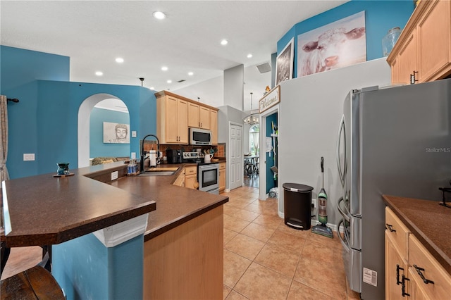 kitchen with appliances with stainless steel finishes, a sink, dark countertops, light brown cabinetry, and recessed lighting