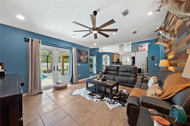 living room with a ceiling fan, french doors, baseboards, light tile patterned flooring, and a textured ceiling