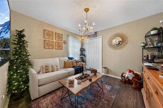 living room with a chandelier, wood finished floors, a textured ceiling, and baseboards