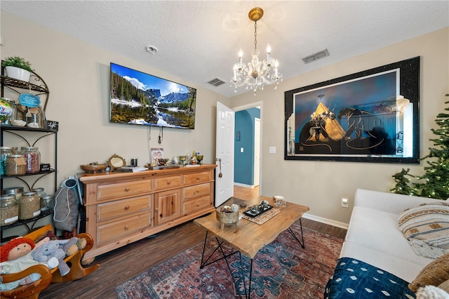 living room with dark wood-style flooring, a chandelier, a textured ceiling, and baseboards