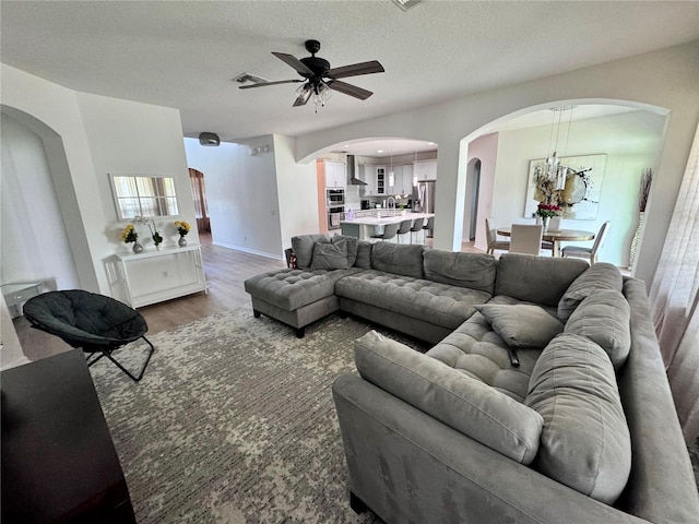 2691 Cypress Tree Trl, Saint Cloud, FL 34772 - living room with ceiling fan, wood finished floors, arched walkways, and a textured ceiling